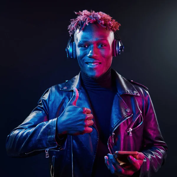 Kulaklıkla dans etmek. Fütürist neon ışıkları. Stüdyodaki Afrikalı Amerikalı genç adam..