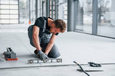 Gri üniformalı adam gündüz vakti modern büyük ofiste kapalı alanda çalışıyor..