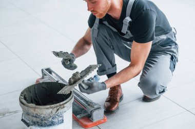 Gri üniformalı adam gündüz vakti modern büyük ofiste kapalı alanda çalışıyor..