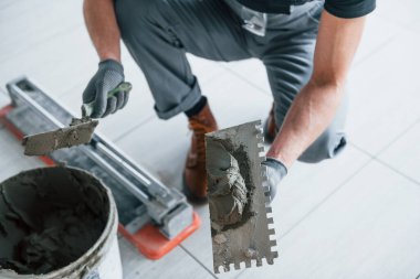 Gri üniformalı adam gündüz vakti modern büyük ofiste kapalı alanda çalışıyor..