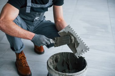 Gri üniformalı adam gündüz vakti modern büyük ofiste kapalı alanda çalışıyor..