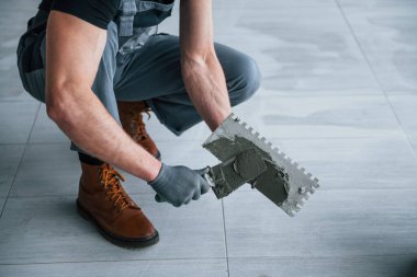 Gri üniformalı adam gündüz vakti modern büyük ofiste kapalı alanda çalışıyor..