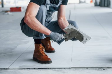 Gri üniformalı adam gündüz vakti modern büyük ofiste kapalı alanda çalışıyor..