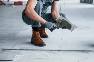 Gri üniformalı adam gündüz vakti modern büyük ofiste kapalı alanda çalışıyor..