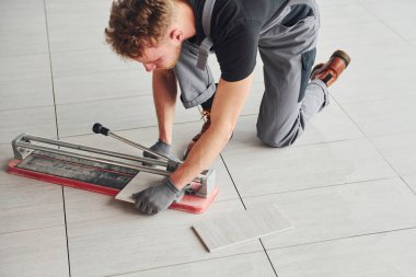 Gri üniformalı bir adam modern büyük ofiste gündüz vakti içeri tabak yerleştiriyor..