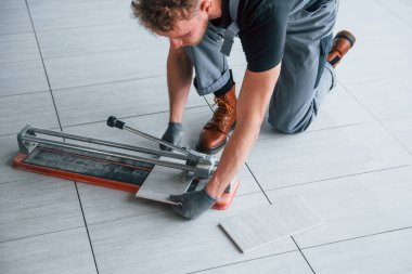 Gri üniformalı bir adam modern büyük ofiste gündüz vakti içeri tabak yerleştiriyor..