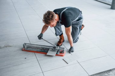 Man in grey uniform installing plate indoors in modern big office at daytime.