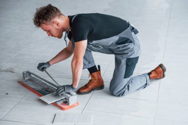 Man in grey uniform installing plate indoors in modern big office at daytime.