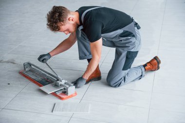 Man in grey uniform installing plate indoors in modern big office at daytime.