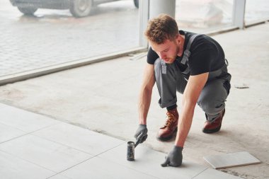 Gri üniformalı bir adam modern büyük ofiste gündüz vakti içeri tabak yerleştiriyor..