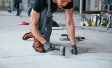 Gri üniformalı bir adam modern büyük ofiste gündüz vakti içeri tabak yerleştiriyor..