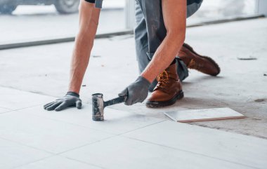 Gri üniformalı bir adam modern büyük ofiste gündüz vakti içeri tabak yerleştiriyor..