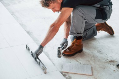 Gri üniformalı bir adam modern büyük ofiste gündüz vakti içeri tabak yerleştiriyor..