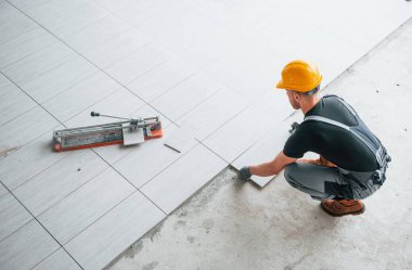 Gri üniformalı bir adamın modern büyük ofisin içinde gündüz vakti tabak yerleştirmesi..