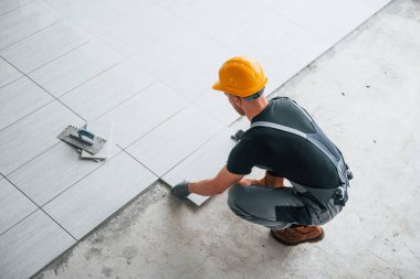 Gri üniformalı bir adamın modern büyük ofisin içinde gündüz vakti tabak yerleştirmesi..