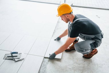 Plakanın kurulumu. Gri üniformalı ve turuncu şapkalı bir adam modern büyük ofiste gündüz vakti çalışıyor..