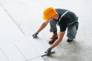 Plakanın kurulumu. Gri üniformalı ve turuncu şapkalı bir adam modern büyük ofiste gündüz vakti çalışıyor..