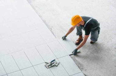 Plakanın kurulumu. Gri üniformalı ve turuncu şapkalı bir adam modern büyük ofiste gündüz vakti çalışıyor..