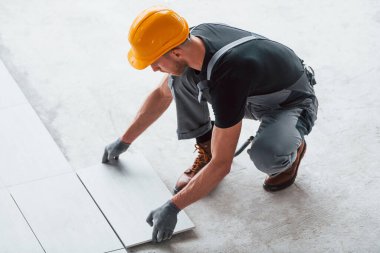 Plakanın kurulumu. Gri üniformalı ve turuncu şapkalı bir adam modern büyük ofiste gündüz vakti çalışıyor..