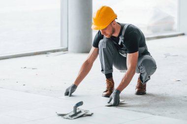 Plakanın kurulumu. Gri üniformalı ve turuncu şapkalı bir adam modern büyük ofiste gündüz vakti çalışıyor..