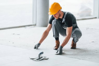 Plakanın kurulumu. Gri üniformalı ve turuncu şapkalı bir adam modern büyük ofiste gündüz vakti çalışıyor..