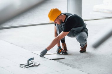 Plakanın kurulumu. Gri üniformalı ve turuncu şapkalı bir adam modern büyük ofiste gündüz vakti çalışıyor..