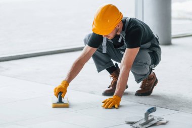 Plakanın kurulumu. Gri üniformalı ve turuncu şapkalı bir adam modern büyük ofiste gündüz vakti çalışıyor..