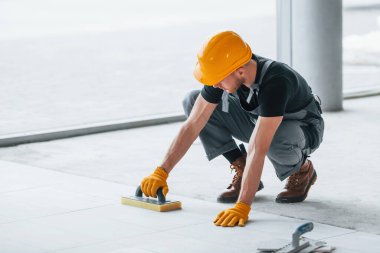 Plakanın kurulumu. Gri üniformalı ve turuncu şapkalı bir adam modern büyük ofiste gündüz vakti çalışıyor..