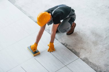 Gri üniformalı bir adamın modern büyük ofisin içinde gündüz vakti tabak yerleştirmesi..