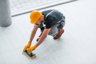 Gri üniformalı bir adamın modern büyük ofisin içinde gündüz vakti tabak yerleştirmesi..