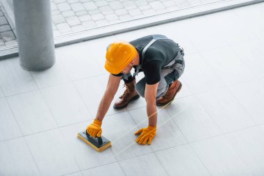 Gri üniformalı bir adamın modern büyük ofisin içinde gündüz vakti tabak yerleştirmesi..