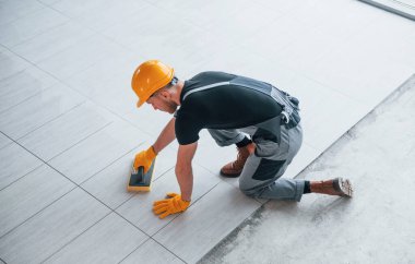 Gri üniformalı bir adamın modern büyük ofisin içinde gündüz vakti tabak yerleştirmesi..