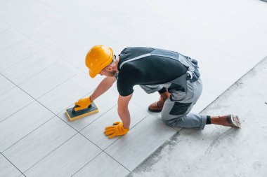 Gri üniformalı bir adamın modern büyük ofisin içinde gündüz vakti tabak yerleştirmesi..