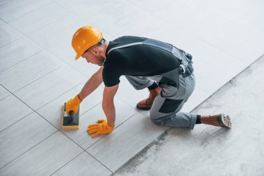 Gri üniformalı bir adamın modern büyük ofisin içinde gündüz vakti tabak yerleştirmesi..