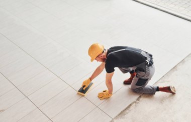 Top view of man in grey uniform that installing plate indoors in modern big office at daytime.