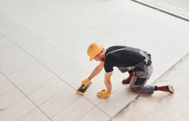 Gri üniformalı bir adamın modern büyük ofisin içinde gündüz vakti tabak yerleştirmesi..