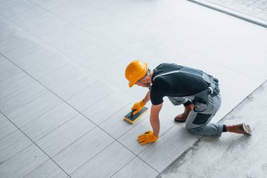 Gri üniformalı bir adamın modern büyük ofisin içinde gündüz vakti tabak yerleştirmesi..