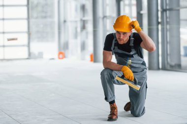 Gündüz vakti modern büyük ofiste gri üniformalı bir adam kameraya poz veriyor..