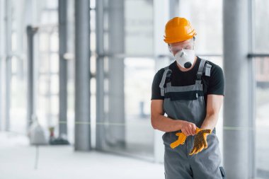 Gri üniformalı adam gündüz vakti modern büyük ofiste çalışmaya hazırlanıyor..