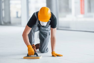 Gri üniformalı adam gündüz vakti modern büyük ofiste çalışıyor..