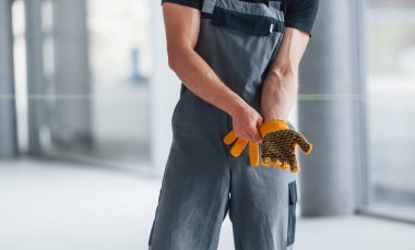 Gri üniformalı adam gündüz vakti modern büyük ofiste çalışmaya hazırlanıyor..