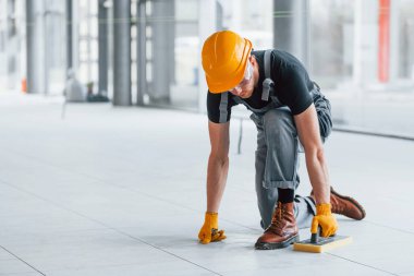 Gri üniformalı adam gündüz vakti modern büyük ofiste çalışıyor..