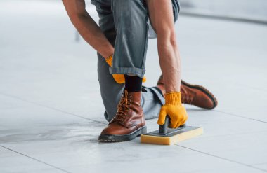 Gündüz vakti modern büyük ofiste kapalı alanda çalışan gri üniformalı adama yakından bakın..