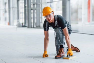 Gri üniformalı adam gündüz vakti modern büyük ofiste çalışıyor..