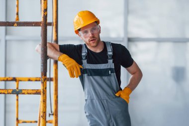 İnşaatın yanındaki gri üniformalı adam modern büyük ofiste gündüz vakti kapalı bir yerde mola veriyor..