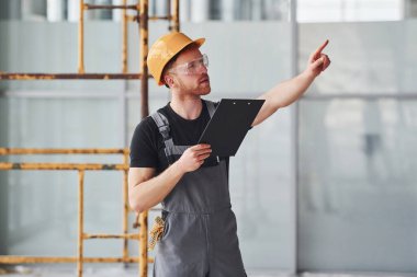 Gri üniformalı genç bir mühendis. Gündüz vakti modern büyük ofiste çalışıyor..