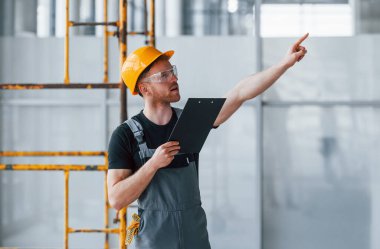 Gri üniformalı genç bir mühendis. Gündüz vakti modern büyük ofiste çalışıyor..