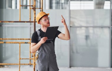 Gri üniformalı genç bir mühendis. Gündüz vakti modern büyük ofiste çalışıyor..