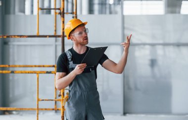 Gri üniformalı genç bir mühendis. Gündüz vakti modern büyük ofiste çalışıyor..