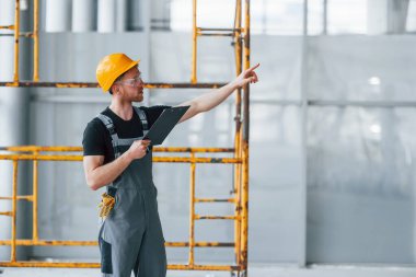 Gri üniformalı genç bir mühendis. Gündüz vakti modern büyük ofiste çalışıyor..